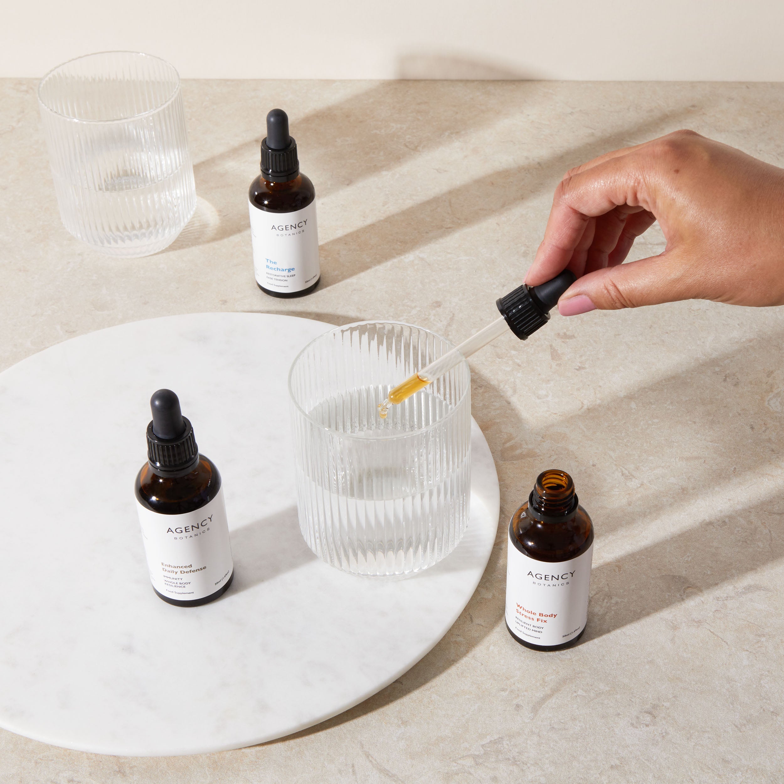 Assortment of organic herbal tinctures and supplements from Agency Botanics for stress (adaptogens), gut health (oregon grape root), immunity (astragalus), menopause (vitex), brain health (Lion's Mane), sleep (passionflower).