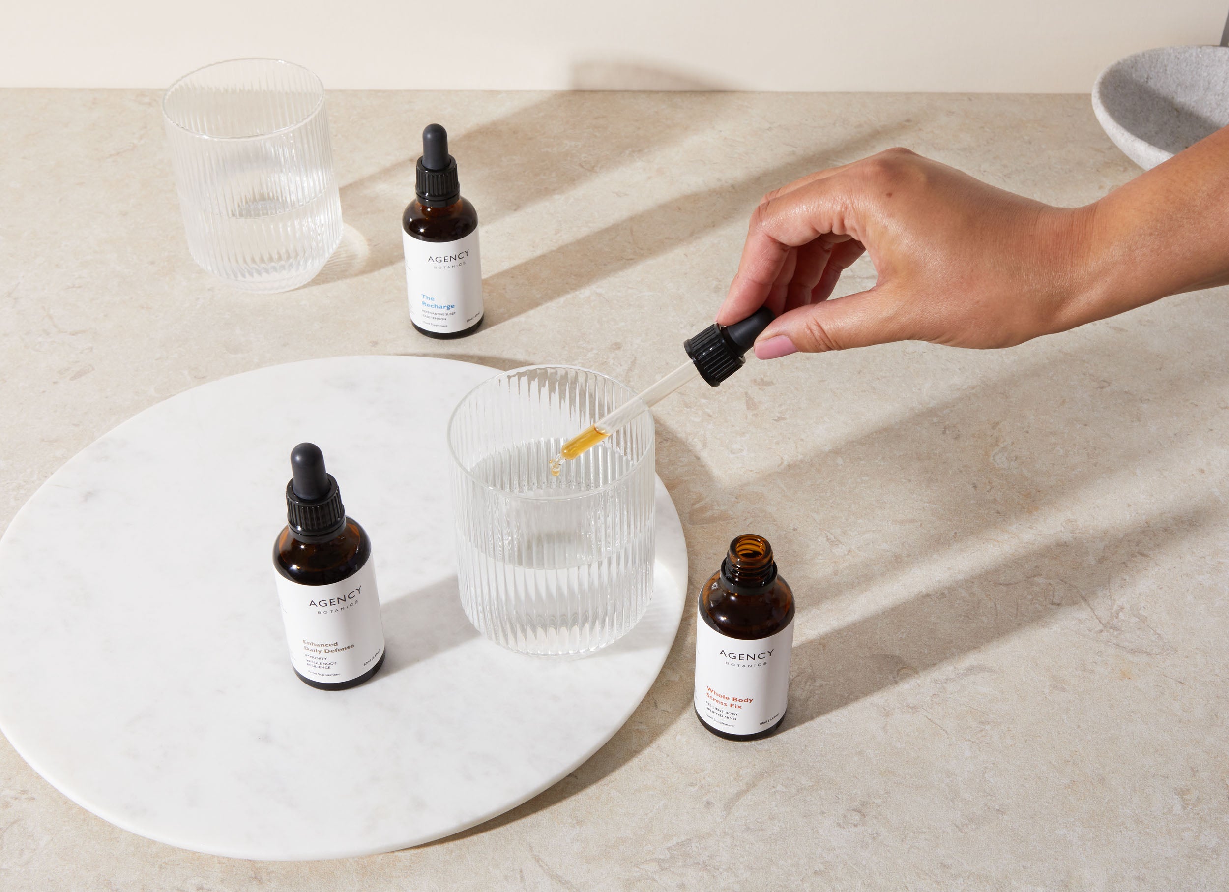 Assortment of organic herbal tinctures and supplements from Agency Botanics for stress (adaptogens), gut health (oregon grape root), immunity (astragalus), menopause (vitex), brain health (Lion's Mane), sleep (passionflower).